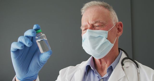 Caucasian senior male doctor wearing face mask holding covid-19 vaccine. covid-19 vaccine and treatment concept
