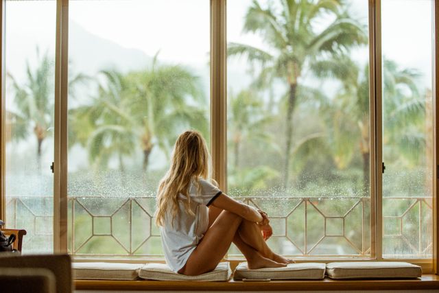 Woman Sitting by Window Looking at Tropical Scenery - Download Free Stock Photos Pikwizard.com