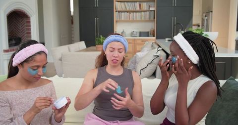 Multiracial women enjoying spa night at home applying under-eye gel patches