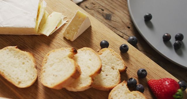 Image of slices of baguette, bluberries and cheese on a wooden surface. food, cuisine and catering ingredients.