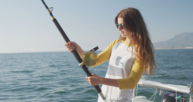 Young woman enjoying a sunny day on a boat while fishing in the sea. Suitable for use in travel, leisure, and outdoor activity brochures, lifestyle blogs, or recreational sport advertisements.