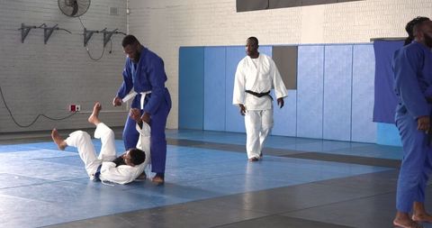 Judo training practice in gym with men throwing on tatami mats