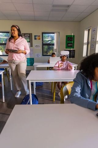 Teacher guiding students with tablets and vr headsets in modern classroom learning