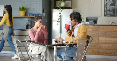 Young african american man and woman chatting over coffee in industrial cafe
