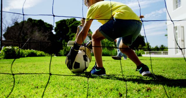 A young child is playing soccer in a backyard, capturing a moment of active play outdoors - Download Free Stock Photos Pikwizard.com