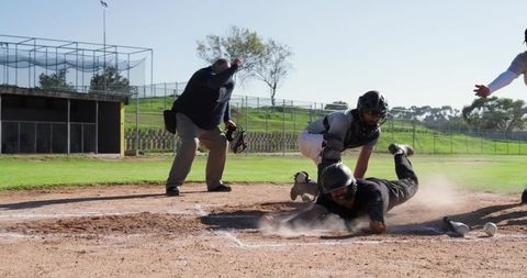 Dramatic home plate sliding play with catcher tagging and umpire calling close play