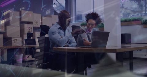 Coworkers Collaborating on Laptop Data Analysis in Modern Office