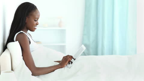 Woman Relaxing in Bed Using Tablet Device