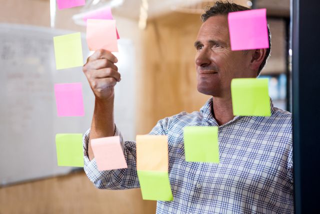Man looking at sticky notes on window in the office
