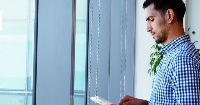 Professional Man Reading His Tablet by the Window in Office - Download Free Stock Images Pikwizard.com