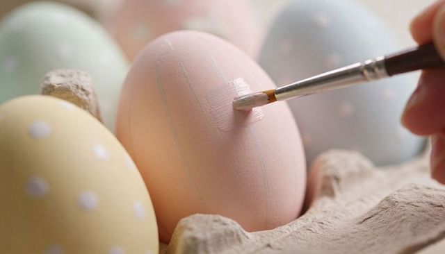 Hand painting pastel easter eggs close-up with brush, delicate polka dot and stripe craft