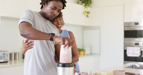 African American Couple Making Pink Smoothie Together in Bright Modern Minimalist Kitchen