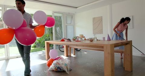 Couple preparing home venue with bright balloons for festive event
