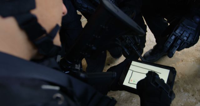 Capturing special forces using a tablet for tactical planning. Useful for topics related to modern military operations, strategic planning, teamwork, and high-tech surveillance equipment. Suitable for blogs, articles, presentations, and training materials highlighting technology in military activities.