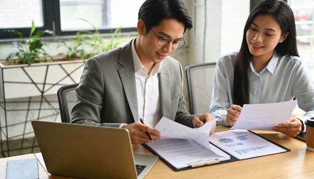 Colleagues reviewing financial reports and charts at modern bright office desk