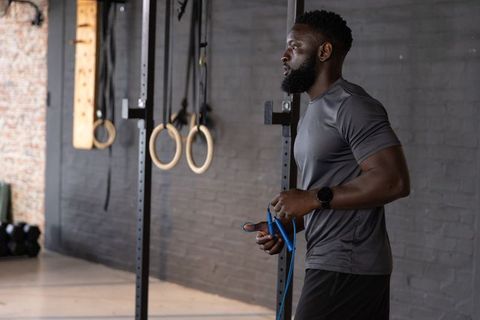 African american fitness athlete preparing jump rope by gymnastic rings on metal rig