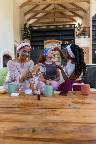 African american friends enjoying at-home spa night with face masks and headbands
