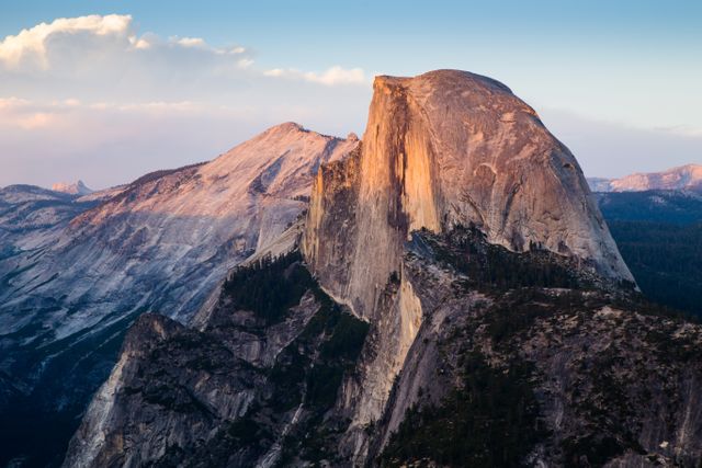 Brilliant sunset light illuminates the iconic Half Dome in Yosemite National Park, highlighting the stunning granite cliffs and natural beauty of California's most renowned national park. Ideal for use in travel blogs, environmental campaigns, adventure tourism promotions, and postcards.