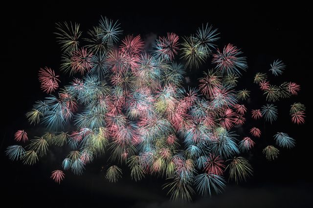 Vibrant bursting fireworks against a dark sky, ideal for usage in event promotion materials, festive greeting cards, and holiday celebration announcements. Perfect as background for community events, New Year's Eve, Independence Day, or any celebratory advertisements.