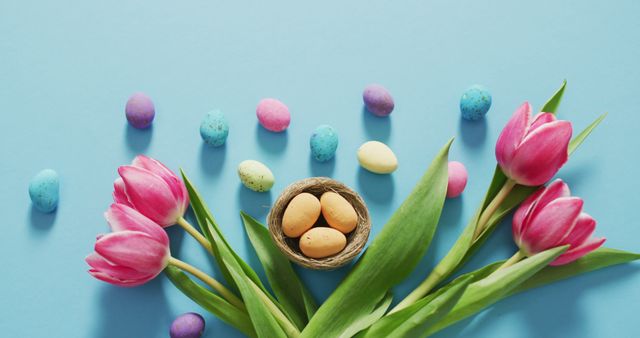 Image of decorated colorful easter eggs and flowers on a blue surface. seasonal easter traditional sweet treats.