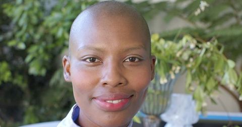 Confident african woman smiling closeup looking at camera outdoors with shaved head