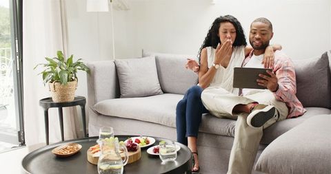 Couple Relaxing on Sofa Using Tablet Video Call