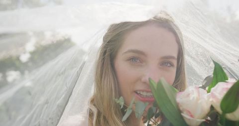 Smiling bride with veil and flowers outdoors