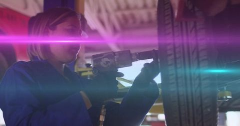 Auto Mechanic Waorking with Impact Wrench on Car Wheel in Garage