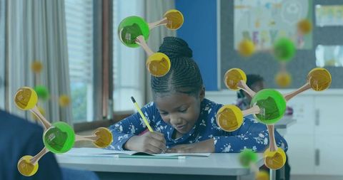 Young student writing at desk with floating augmented molecular models during STEM class