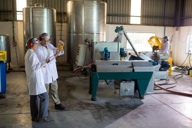 Technicians examining olive oil in factory