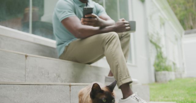 Man Relaxing with Smartphone and Coffee, Siamese Cat Nearby - Download Free Stock Images Pikwizard.com