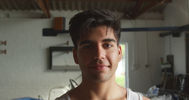 Young Man Smiling in Workshop Wearing White Tank Top - Download Free Stock Images Pikwizard.com