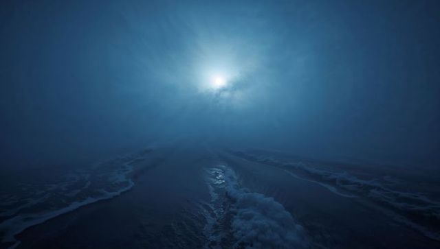 Luminous orb piercing low fog over midnight ocean with foamy wave channels reflecting glow