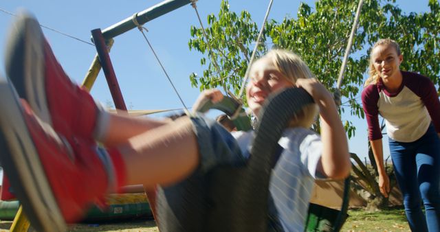 Boy Swinging on Playground Swing with Happy Woman Pushing - Download Free Stock Images Pikwizard.com