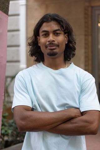 Confident african american man standing arms crossed wearing light blue tee urban portrait