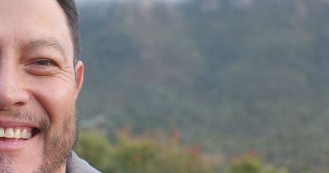 Middle-aged Man Smiling Brightly on Scenic Mountain Slope