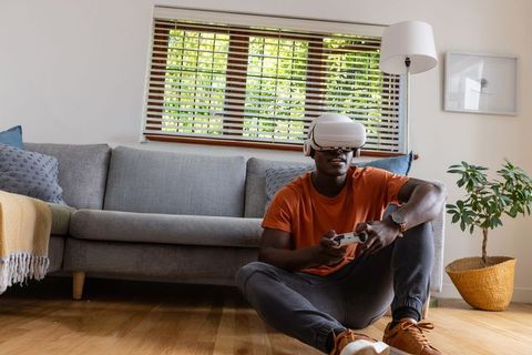 Young african american man wearing vr headset gaming in cozy living room