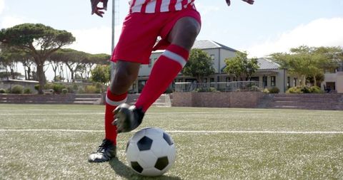 Athlete dribbling soccer ball on turf in red-and-white stripes