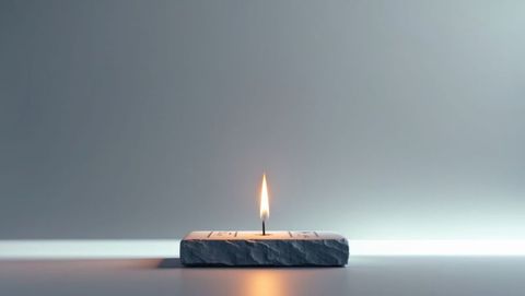 Solitary wax candle burning in stone holder with minimal design