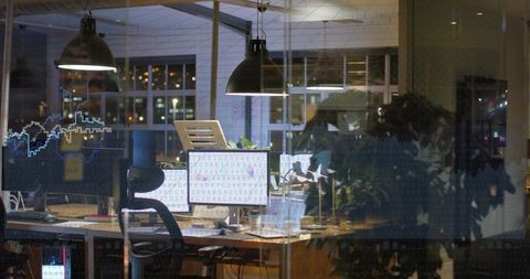 Nighttime tech workspace showing dual monitors displaying code, laptop, city reflections