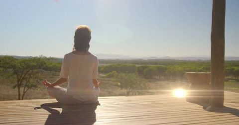 Serene Woman Meditating on Sunlit Platform in Nature