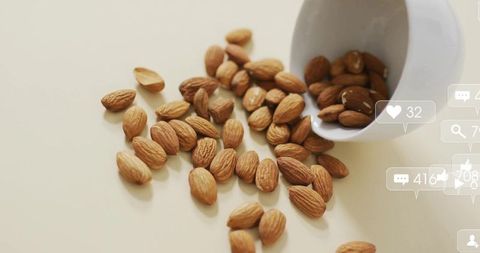 Spilled almonds from ceramic cup with social media elements