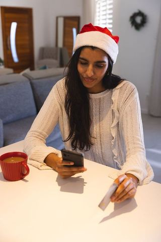 Woman celebrating christmas with online shopping on phone at home