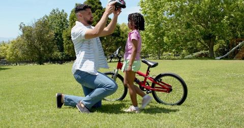 Father and Daughter Preparing for Bicycle Ride in Sunny Park