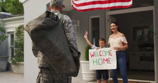 Happy caucasian male soldier greeting son and wife with welcome home sign outside their house. soldier returning home to family.