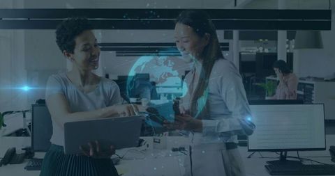 Two Women Collaborating on Technology Project in Modern Office