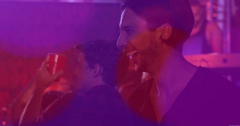 Bearded Man Socializing in Nightclub with Vivid Lighting
