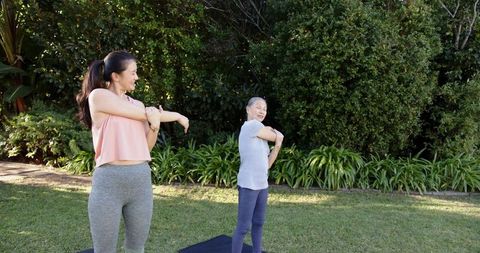 Mother and daughter stretching in sunny garden for wellness and harmony