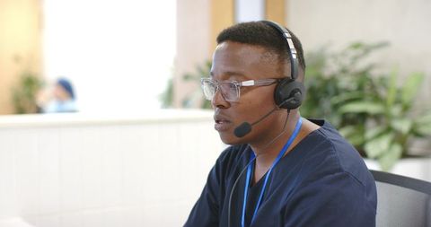 Healthcare call center representative wearing headset and scrubs at reception desk