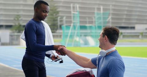 Athletes Sharing Equipment on Outdoor Track Highlighting Team Spirit
